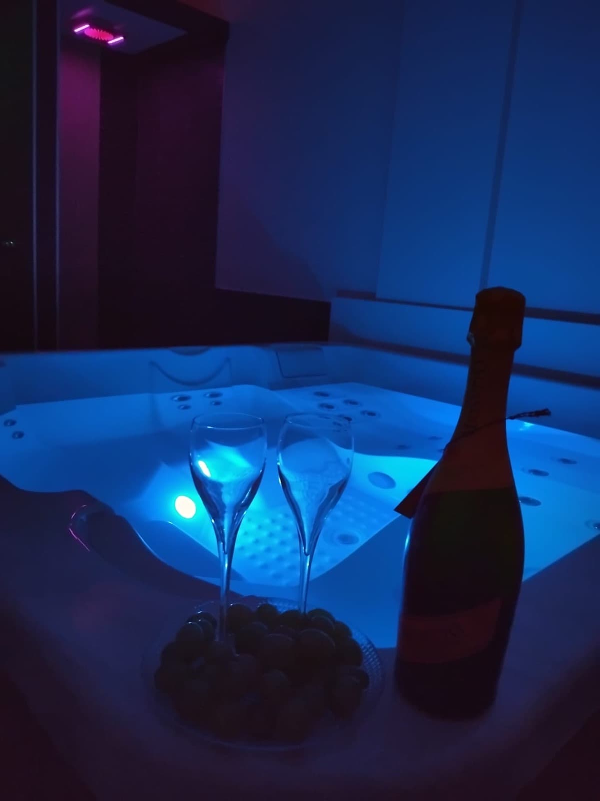 Vasca idromassaggio con calici, bottiglia di prosecco e frutta fresca a bordo vasca